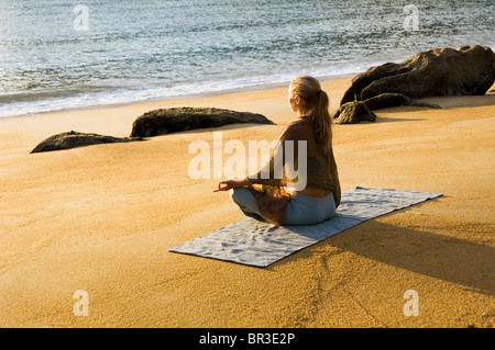 Une femme pratiquant le yoga sur une plage au parc national Abel Tasman. L'île du Sud, Nouvelle-Zélande. Banque D'Images