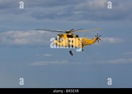 Sea King RAF hélicoptère de sauvetage, un winchman abaisse sur un bateau de sauvetage côtiers de la RNLI en attente. Banque D'Images