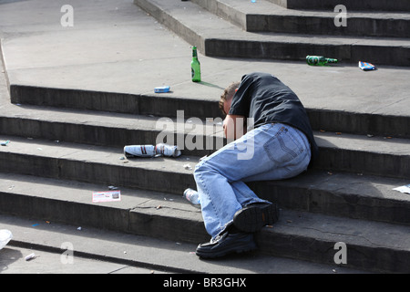Jeune homme étendu endormi sur les étapes d'Eros après avoir bu de l'alcool, Piccadilly Circus, Westminster, London, W1. Banque D'Images