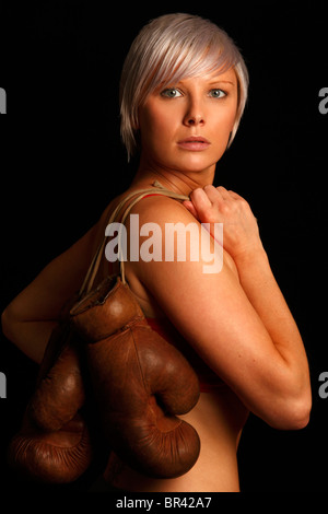 Jeune femme avec des cheveux gris d'argent tenant une vieille paire de gants de boxe Banque D'Images