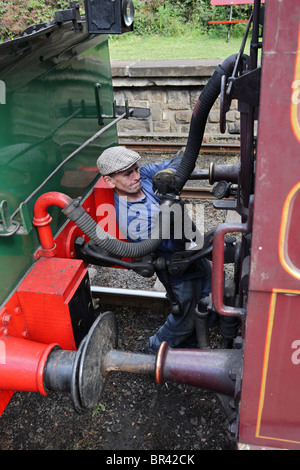 Le conducteur d'une machine à vapeur des couples le tuyau de frein vide de la loco au train. Gare Tanfield, Gateshead, England, UK Banque D'Images