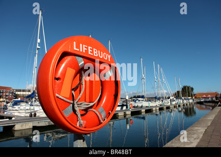 Bouée orange ronde sur le post à Weymouth ou le port de port blanc avec des yachts de luxe dans l'arrière-plan Banque D'Images