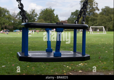 Un swing de l'enfant bleu siège dans une aire de jeux pour enfants sur la place du village dans la région de Jordans Buckinghamshire UK Banque D'Images