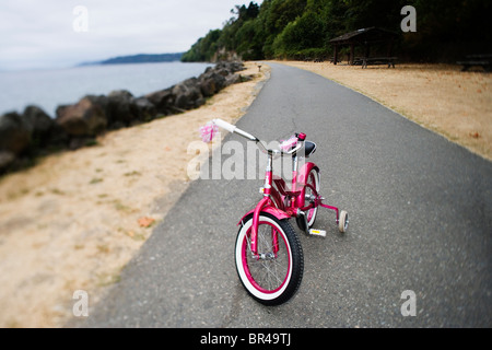 Un peu de rose, vélo avec roues d'entraînement gauche le long d'un sentier dans l'eau salée State Park, Des Moines, Washington. Banque D'Images