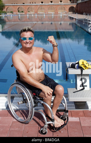 Les jeunes, homme handicapé dans un fauteuil roulant, des exercices de natation, piscine edge, balled fist Banque D'Images