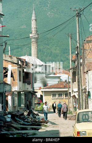 Les gens à pied la rue passé la destruction à Peja, au Kosovo. Banque D'Images