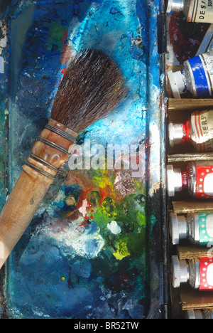 L'utilisation de l'artiste vintage de blaireau pinceau, sur une aquarelle de l'artiste,meubles, paintbox avec palette de mélange et des tubes de peinture. Banque D'Images