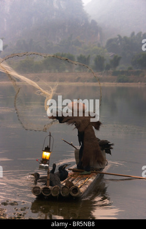 Le port de pêcheur avec couche de paille cormorans sur radeau en bambou casting filet de pêche sur la rivière Li au crépuscule, Yangshuo, Guangxi, Chine Banque D'Images