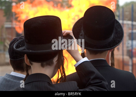 Des écoliers juifs orthodoxes de l'école Bobov regarder leur Lag Baomer grand feu dans la cour de l'école. Banque D'Images