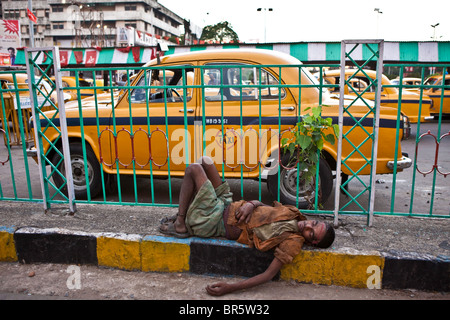 Un sans-abri se trouve endormi sur le trottoir devant la gare de Calcutta. Banque D'Images