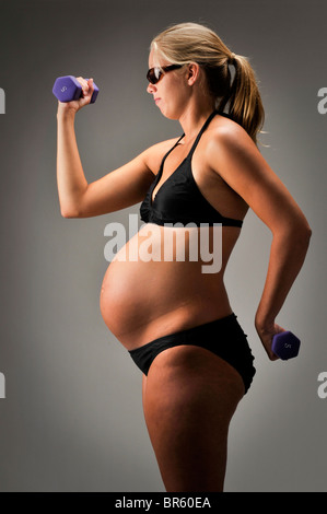 Femme enceinte avec accessoires et maillot noir sur fond blanc. Banque D'Images