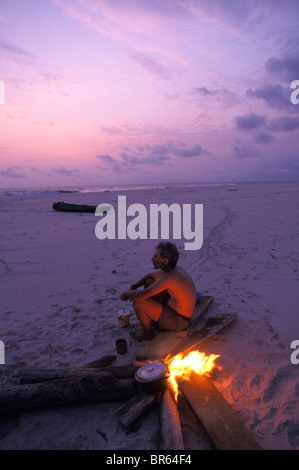 Mike Fay jouit d'un coucher du soleil par un feu sur une plage éloignée du Gabon dans le Parc National de Loango. Banque D'Images