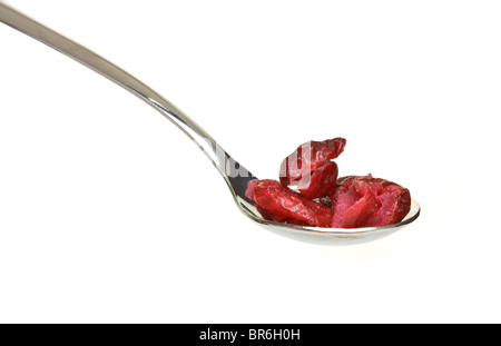 Cuillère en argent empilé avec fruits secs de la canneberge isolé sur blanc. Banque D'Images