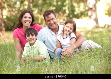 Family Sitting in Long Grass In Park Banque D'Images