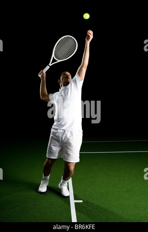 Un joueur de tennis au service d'une balle, portrait, studio shot Banque D'Images