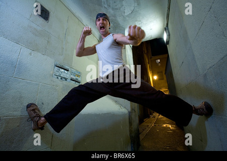 Homme portant un bandeau faisant le grand écart entre deux murs détient ses poings tout en criant la France. Banque D'Images