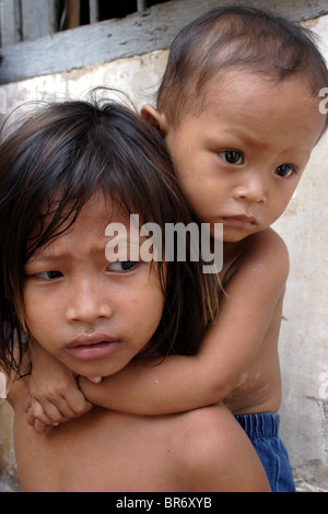 Une jeune fille khmère porte un jeune garçon dans un temple près d'un village de squatteurs à Phnom Penh, Cambodge. Banque D'Images