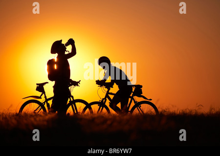 L'homme en prenant un verre d'une bouteille d'eau et la femme en vtt vélo sur Hambledon colline au-dessus de la vallée de Blackmore, Dorset, E Banque D'Images