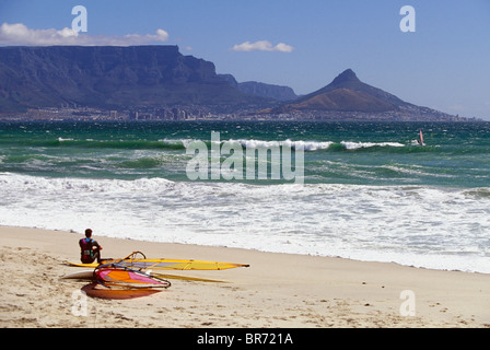 Une planche en faisant une pause sur une plage de sable donnant sur le cap, Table Mountain et Lion's Head, Afrique du Sud. Banque D'Images