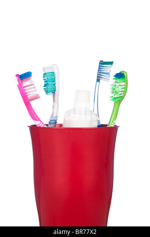 Des brosses à dents et un tube de dentifrice dans un gobelet isolé sur blanc. Banque D'Images