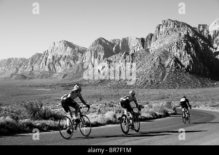 Trois coureurs descendant la route panoramique dans le Red Rock Canyon de conservation. Banque D'Images