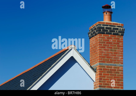 Une vue en gros plan d'une cheminée en brique sur une maison, sous un ciel bleu clair. Banque D'Images