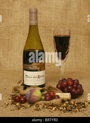 Bouteille de vin rouge et de vin dans un verre, avec des fruits sur un fond de toile. Banque D'Images