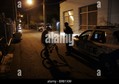 La CDP de la police de Vancouver s'adresse à un jeune sur un vélo dans une ruelle la nuit, Vancouver, British Columbia, Canada Banque D'Images