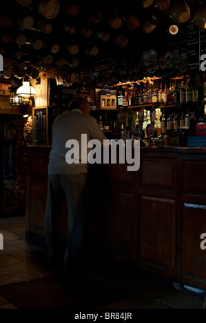 Un homme âgé se tient au comptoir des îles Falkland Arms Public House dans Great Tew, Oxfordshire Banque D'Images