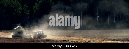 Photo panoramique des agriculteurs travaillant avec une moissonneuse-batteuse et le tracteur la récolte la récolte dans un champ. L'automne, l'Estonie. Banque D'Images