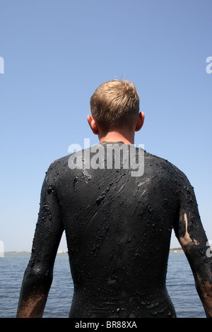 Tourner d'un jeune homme couvert de boue dans le lac salé, la ville de Saki, Crimea, Ukraine Banque D'Images