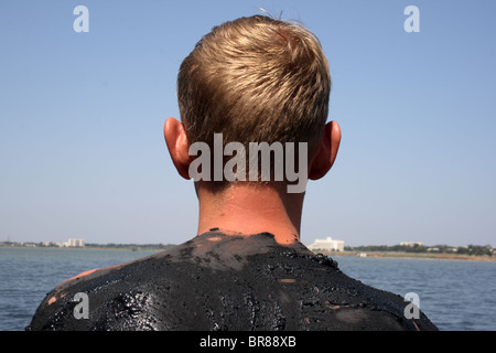 Tourner d'un jeune homme couvert de boue dans le lac salé, la ville de Saki, Crimea, Ukraine Banque D'Images