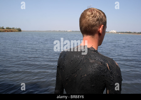 Tourner d'un jeune homme couvert de boue dans le lac salé, la ville de Saki, Crimea, Ukraine Banque D'Images