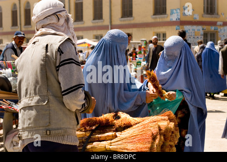 Deux femmes en burqa shop pour balais près de Marché Mandawi à Kaboul. Banque D'Images