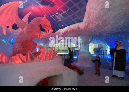 Une famille arabe poser pour des photographies en face d'un dragon sculptés dans la glace à une piste de ski intérieure, centre commercial Mall of the Emirates Banque D'Images