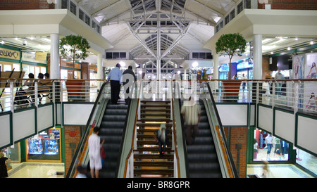 Les clients qui montent et descendent les escaliers mécaniques dans le centre commercial de Victoria Wharf Cape Town Afrique du Sud. Banque D'Images