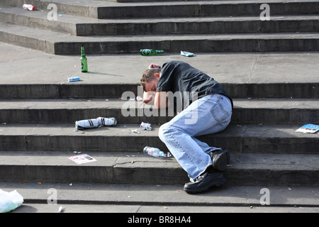 Jeune homme étendu endormi sur les mesures d'Eros après avoir bu de l'alcool, Piccadilly Circus, Westminster, London, W1. Banque D'Images