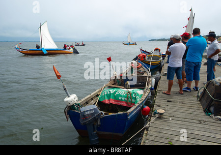 Les sections locales watch de la jetée comme un bateau traditionnel Moliceiro met les voiles de Torreira à Aveiro, Portugal Banque D'Images