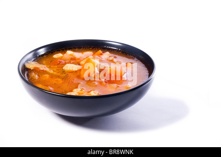 L'Italien minestrone, soupe de légumes, dans un bol noir. Isolé sur blanc. Banque D'Images