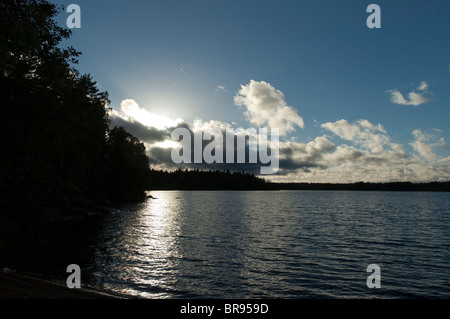 Bien briser à travers les nuages qui se reflète sur le lac en Suède Banque D'Images