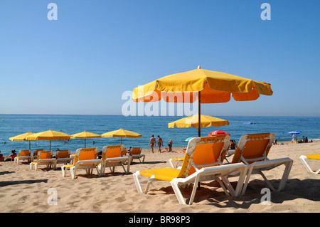 Chaises de plage / chaises longues et des parasols sur la plage de Calella par la mer Méditerranée. Banque D'Images