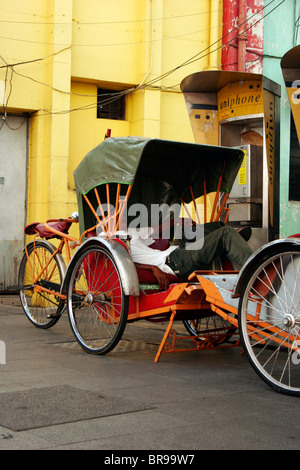 Conducteur de pousse-pousse se reposant à George Town, l'île de Penang, Malaisie Banque D'Images