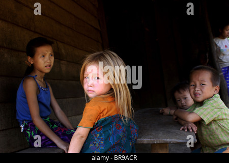 Enfants Hmongs vous détendre sur la véranda de leur maison à seulement 15 kilomètres de Luang Prabang, Laos. Banque D'Images