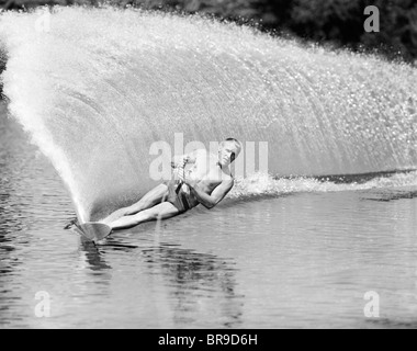 1970 slalom homme se penchant sur le côté pour créer mur d'eau de derrière Banque D'Images