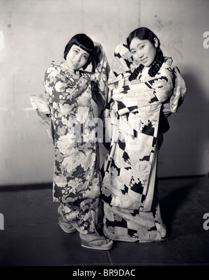 Années 20, DEUX JEUNES FEMMES JAPONAISES POSANT EN KIMONO SMILING AT CAMERA Banque D'Images