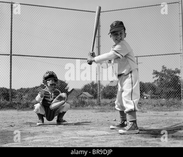 1960 Deux garçons jouer au baseball BATTER ET CATCHER À PLAQUE D'ACCUEIL Banque D'Images