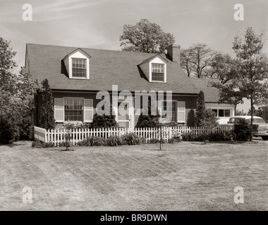 Années 1950 Années 1960 SUBURBAN MAISON EN BRIQUE PICKET FENCE LUCARNES VOITURE DANS L'allée Banque D'Images