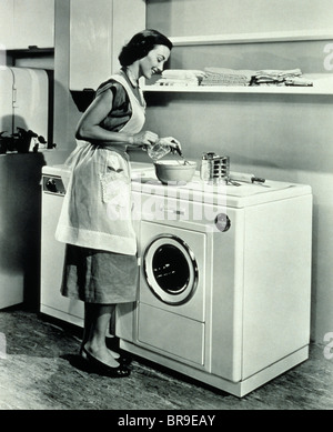 Femme au foyer des années 50 en utilisant le haut du lave-linge Sèche-linge LE CONTRE Banque D'Images