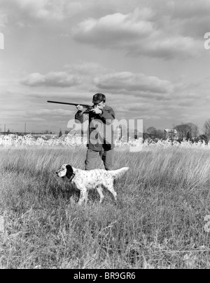 Années 1930 Années 1940 LA CHASSE AUX OISEAUX DE L'HOMME SUR LE TERRAIN AVEC LE CHIEN DE FUSIL VISANT Banque D'Images