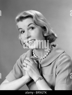 Années 1950 Années 1960 FEMME LES MAINS JOINTES À LA POITRINE PORTANT Collier Perles Banque D'Images